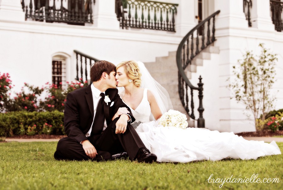 bride and groom sitting on the ground and kissing