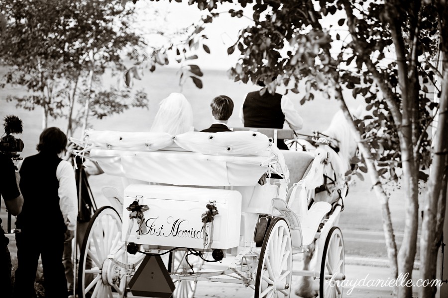 bride and groom riding away in carriage