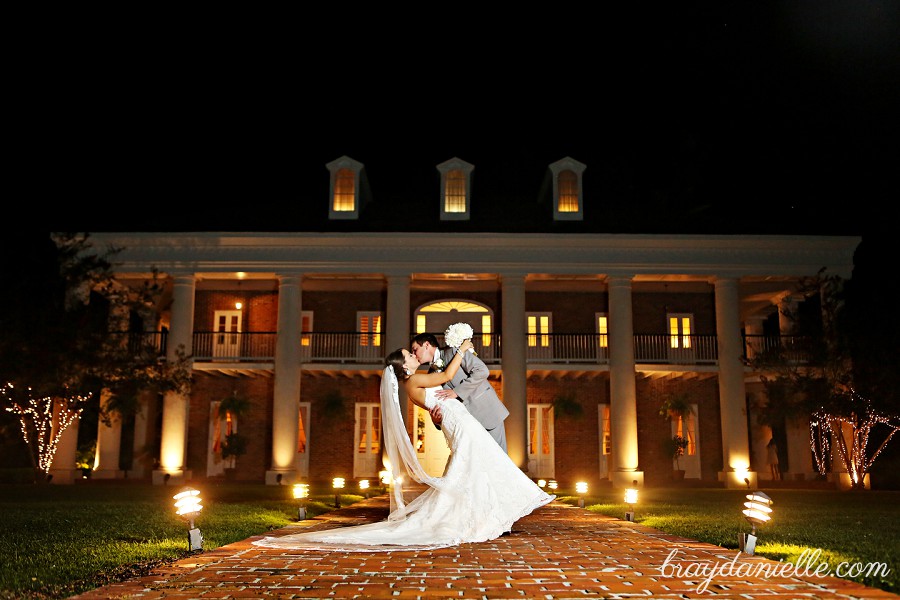 Bride and groom kissing in front of White Oak Plantation at night