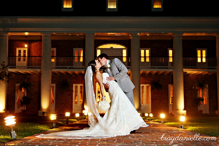 romantic photo of bride and groom kissing in front of white oak plantation