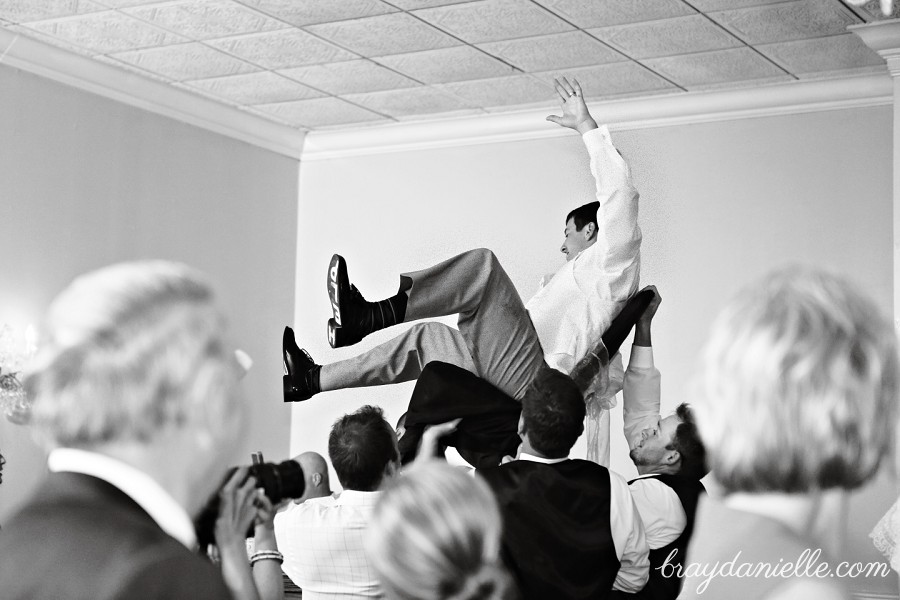 Groom being lifted up in a chair