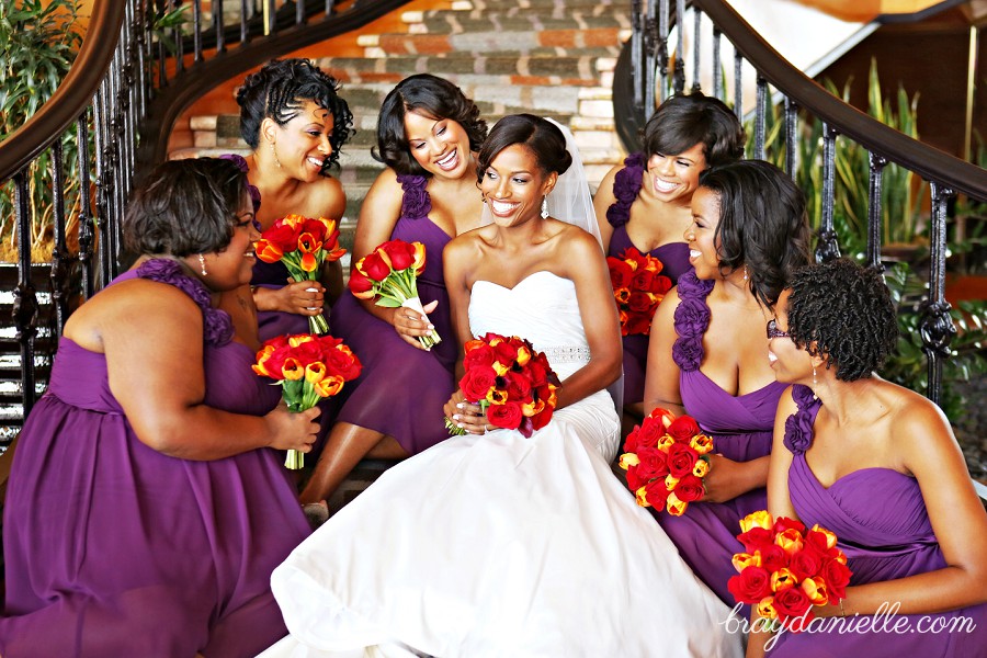 Bridal party posed on steps smiling at the bride purple dresses